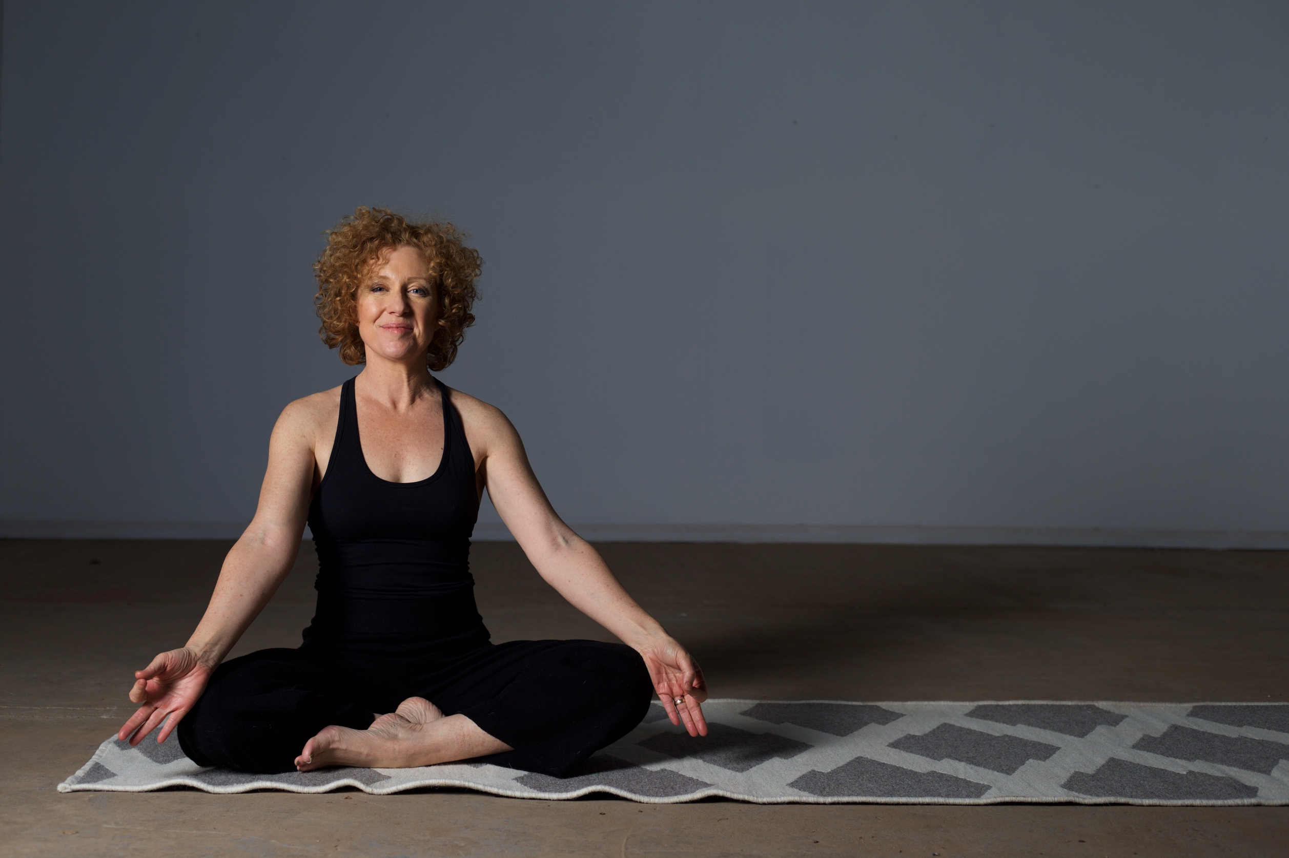 Woman sitting cross legged on yoga mat