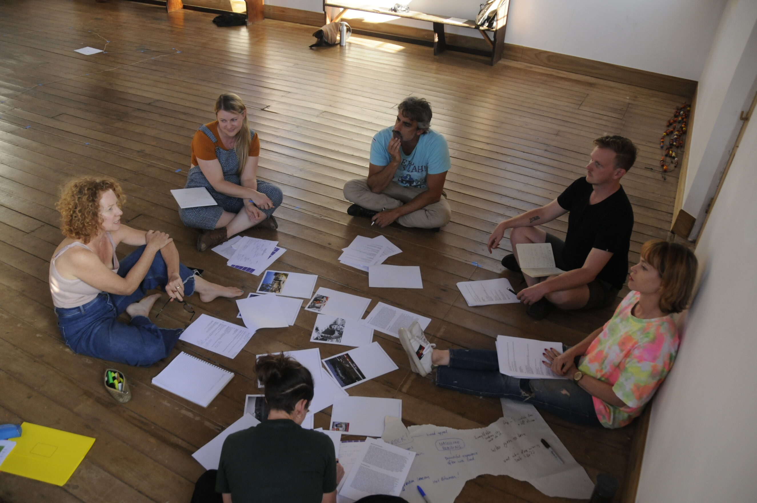 Group of people siting in a circle with papers around them